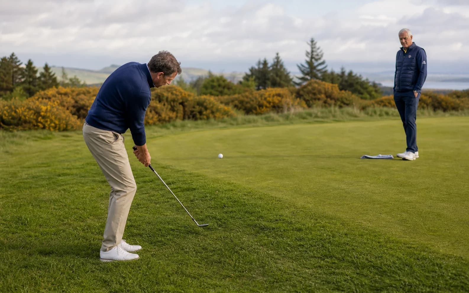 A golfer playing a small chip toward a landing area on the green