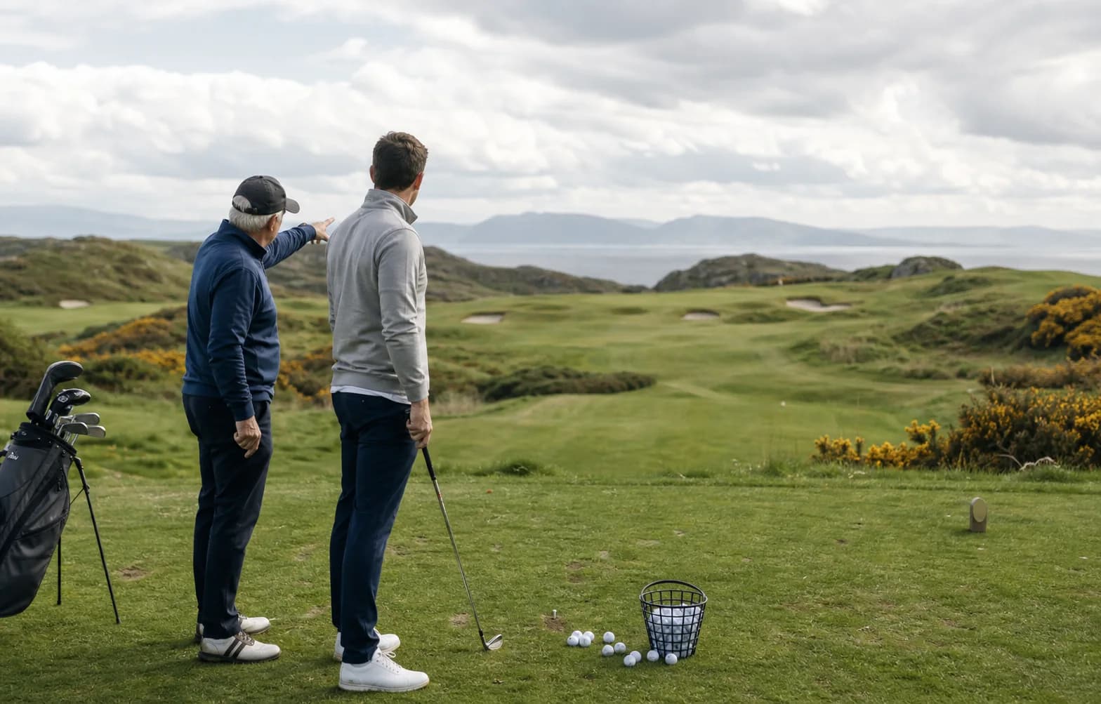 A coach and golfer choosing a target from a practice tee toward the course